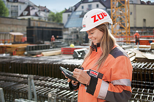Foto af en byggeleder, der redigerer noget på sin tablet, mens hun står på byggepladsen