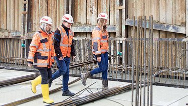 Foto af tre ZÜBLIN-kolleger, der går hen over byggepladsen