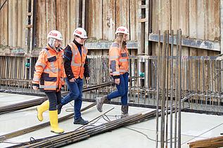 Foto af tre ZÜBLIN-kolleger, der går hen over byggepladsen
