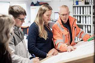 Foto af ZÜBLIN-kolleger, der diskuterer noget på baggrund af en byggeplan
